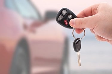 a hand holding car keys and a remote control for keyless entry isolated over white HYswXvCSj
